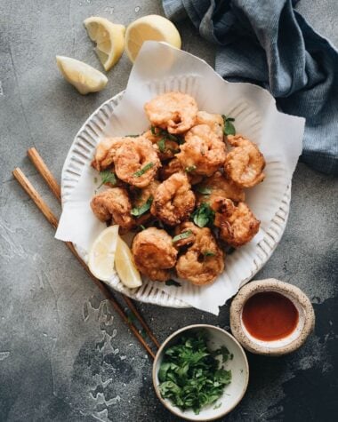 Fried shrimp served in plate with parchment paper with chopped cilantro and sauce on the side