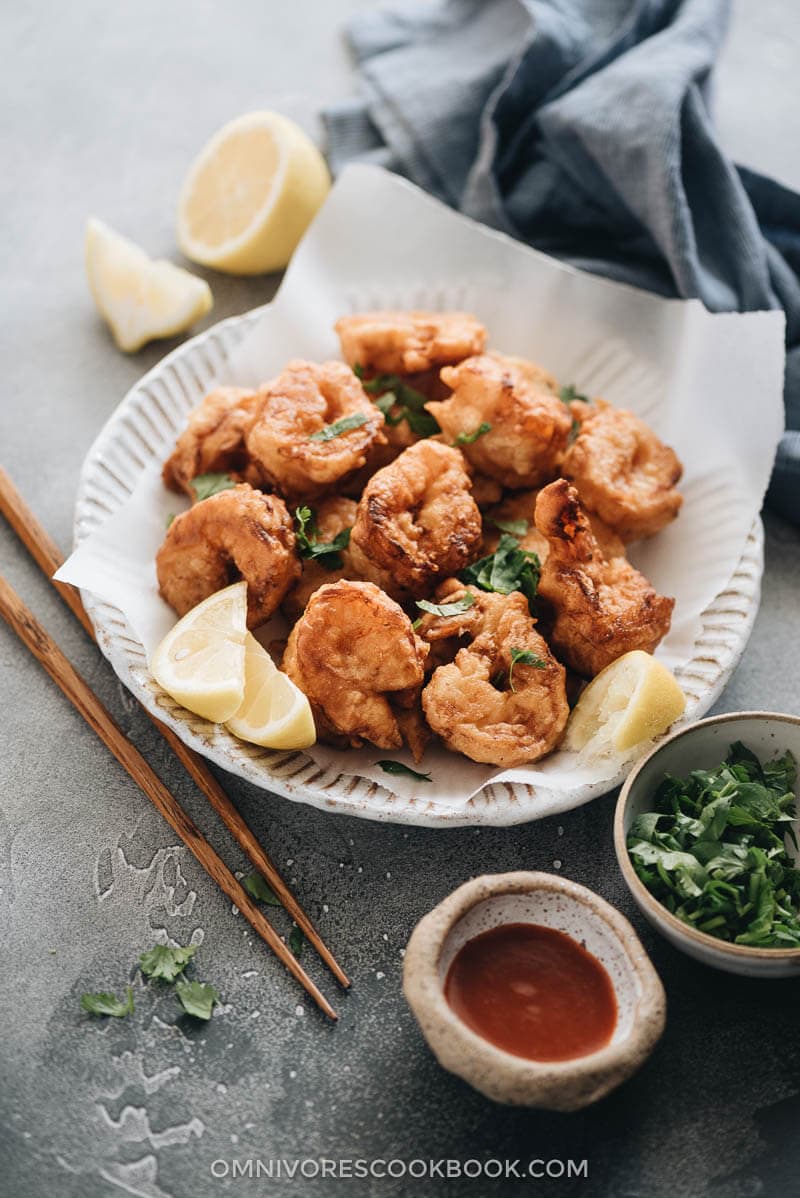 3-Ingredient Fried Shrimp is the easiest fried shrimp recipe that generates the best results. The juicy shrimp are wrapped in a light, crispy, and fluffy crust that is similar to tempura. So good! #seafood #recipes #shrimp Fried shrimp served in plate with parchment paper closeup