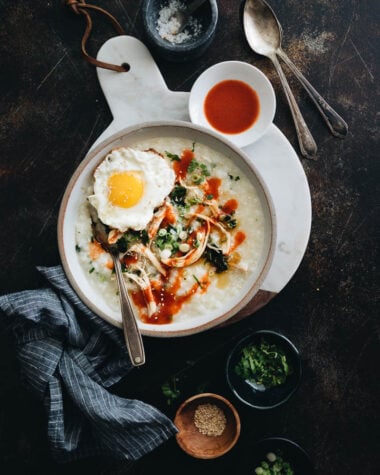 Instant Pot congee with chicken and spinach topped with egg served in a bowl with sauce and toppings on the side