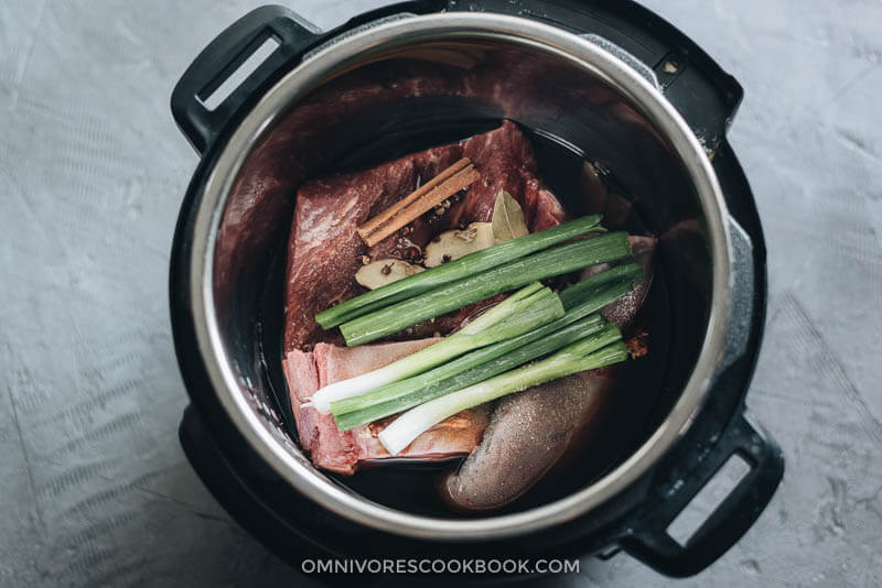 This Fu Qi Fei Pian (Sichuan Sliced Beef in Chili Sauce) recipe gives you the real-deal Sichuan experience. The tender beef slices are served in a rich, spicy hot sauce and topped with peanut flakes and cilantro. #glutenfree #beef #instantpot #chinese #recipes Beef brisket and beef tongue with seasonings in Instant Pot