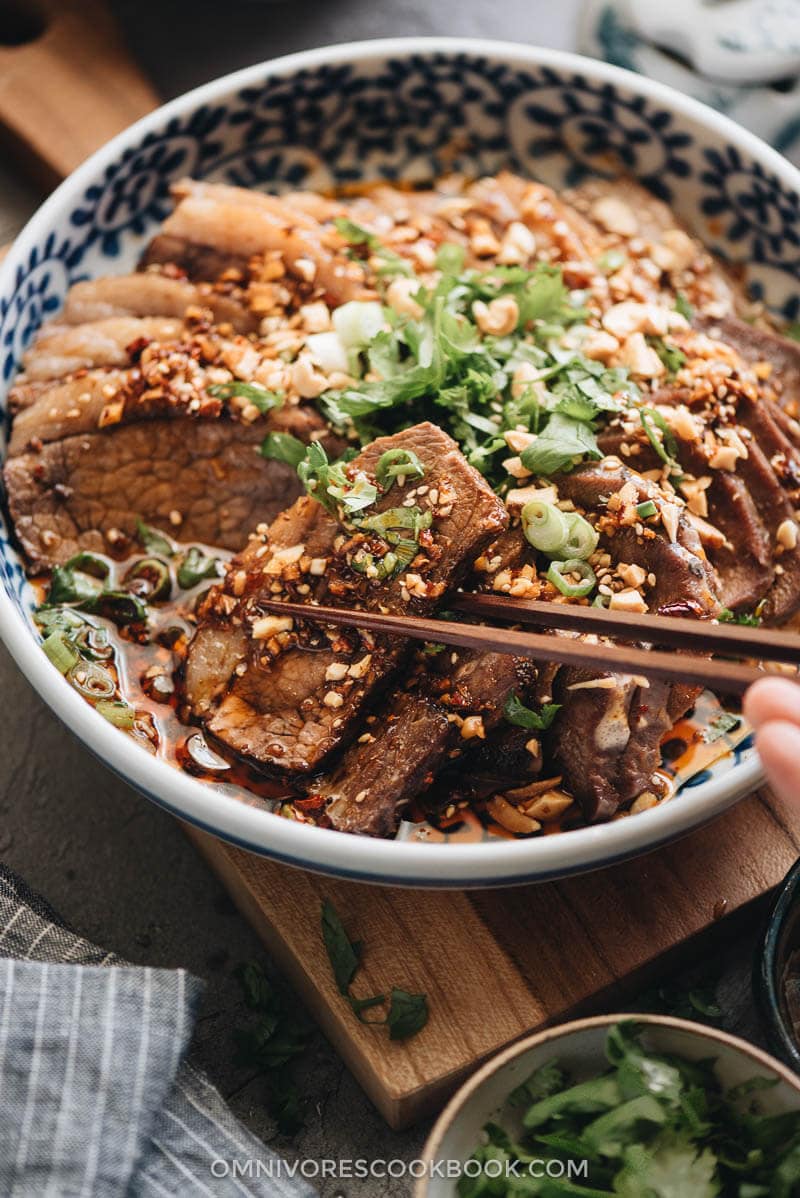 This Fu Qi Fei Pian (Sichuan Sliced Beef in Chili Sauce) recipe gives you the real-deal Sichuan experience. The tender beef slices are served in a rich, spicy hot sauce and topped with peanut flakes and cilantro. #glutenfree #beef #instantpot #chinese #recipes Picking a piece of beef brisket from Fu Qi Fei Pian plate