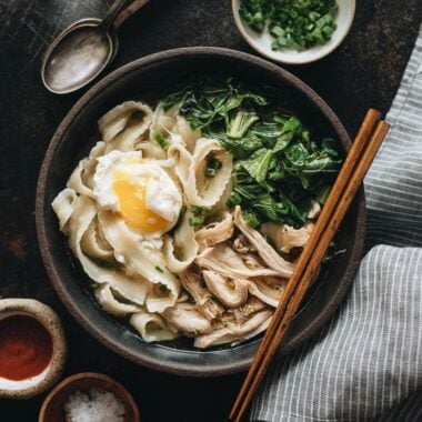 One bowl of Instant Pot chicken noodle soup with Sriracha and salt on the side