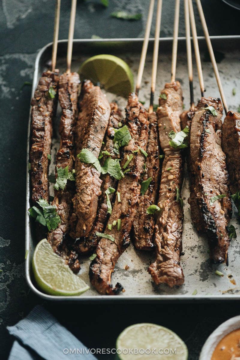 Beef Satay - Skewers of flavorful beef get that perfect char over the Chinese grill and are served with a sweet, tangy and totally craveable peanut sauce. #marinade #recipe #sticks #gluten-free Beef satay served with peanut sauce and cilantro close up