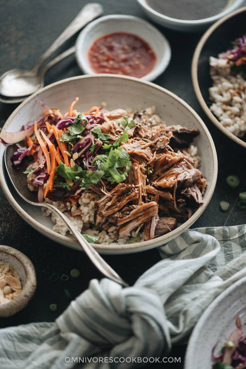 Asian-Style Instant Pot Pulled Pork - Tender, juicy pork with a melt-in-your-mouth texture made in a rich Asian sauce. It’s just about everything you need for a weekday dinner because it takes no time to put together. #easy #glutenfree #recipe #shoulder Asian Instant Pot pulled pork served on steamed brown rice and coleslaw closeup
