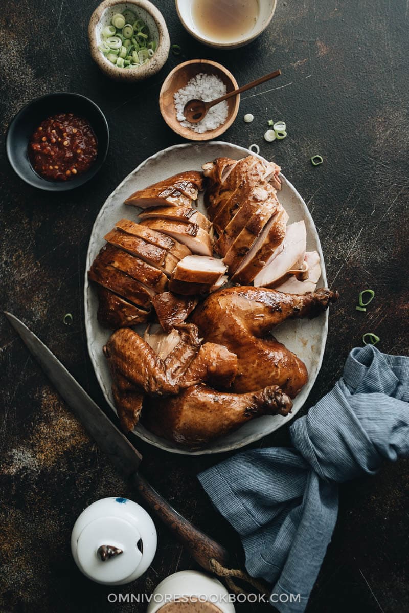 Chinese Soy Sauce Chicken - This homemade soy sauce chicken has silky tender meat with a deep savory flavor. Learn how easy it is to make this Cantonese dim sum at home and even achieve restaurant taste. #marinade #recipe #healthy #glutenfree #brownsugar Sliced soy sauce chicken served with Sriracha, salt, and green onions