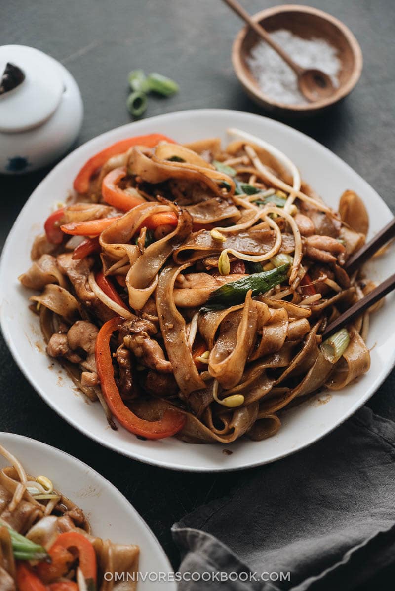 15-Minute Chicken Chow fun - This chicken fried noodle recipe is super fast to make and yields restaurant-style results. The dish is loaded with fat rice noodles, tender chicken, and crisp veggies. No wok required! #recipe #comfortfood #stirfry #glutenfree Restaurant style chicken chow fun with bean sprouts and peppers