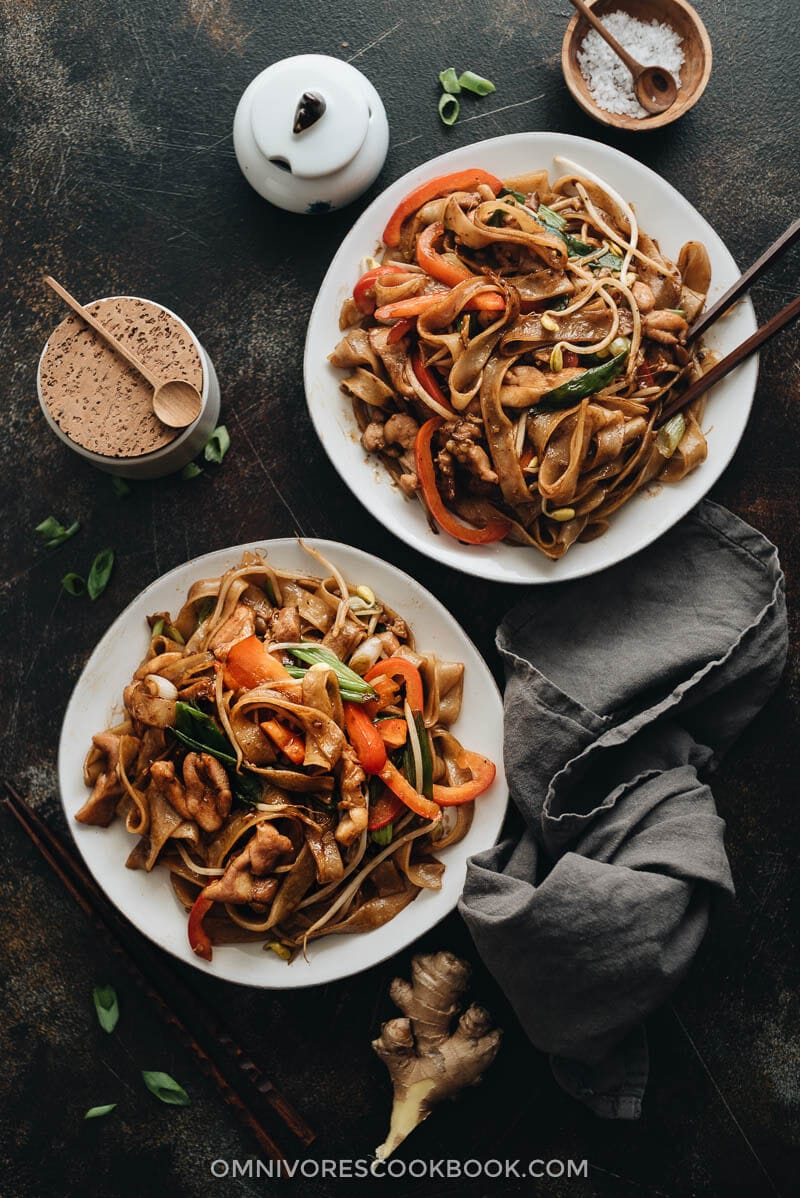 15-Minute Chicken Chow fun - This chicken fried noodle recipe is super fast to make and yields restaurant-style results. The dish is loaded with fat rice noodles, tender chicken, and crisp veggies. No wok required! #recipe #comfortfood #stirfry #glutenfree 15-minute chicken chow fun served in plates