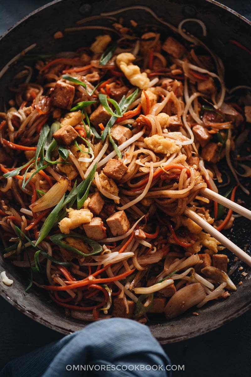 Vegan Pad Thai - The fat noodles are stir-fried with plenty of aromatics, veggies, vegan eggs, and marinated tofu in an extra rich sweet and sour sauce. Detailed cooking notes are included to guarantee you a great result that tastes even better than the restaurant version. {Gluten-Free adaptable} Homemade vegan Pad Thai in a pan close up