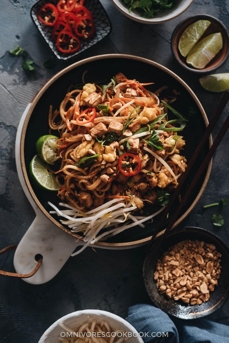 Vegan Pad Thai - The fat noodles are stir-fried with plenty of aromatics, veggies, vegan eggs, and marinated tofu in an extra rich sweet and sour sauce. Detailed cooking notes are included to guarantee you a great result that tastes even better than the restaurant version. {Gluten-Free adaptable} Vegan Pad Thai garnished with bean sprouts and lime