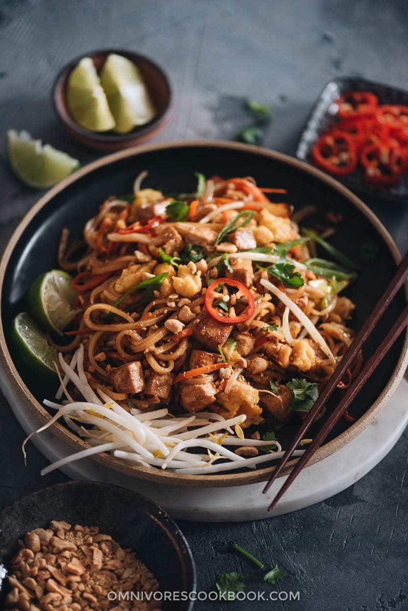 Vegan Pad Thai - The fat noodles are stir-fried with plenty of aromatics, veggies, vegan eggs, and marinated tofu in an extra rich sweet and sour sauce. Detailed cooking notes are included to guarantee you a great result that tastes even better than the restaurant version. {Gluten-Free adaptable} Vegan Pad Thai in a plate