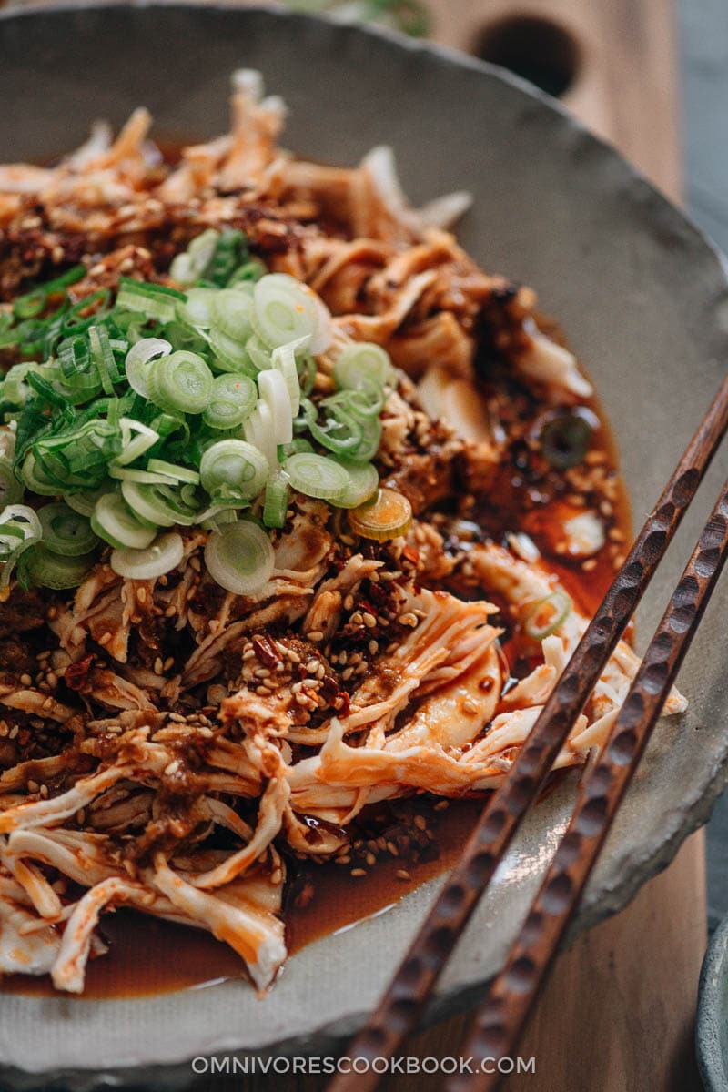 Chinese Bang Bang Chicken (棒棒鸡) - The real-deal Sichuan version of Bang Bang chicken made with juicy tender shredded chicken breast covered with a savory, nutty, spicy sauce with a hint of tangy and sweet notes. Originally a traditional Chinese appetizer, make it ahead and serve it at your next movie night or game day party. Mind blow guaranteed. Sichuan-style shredded chicken in red oil close-up