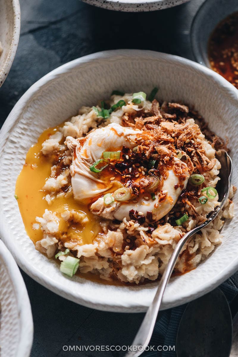 5-Ingredient Savory Oatmeal (Chinese-Style) | This oatmeal is simmered with chicken stock until creamy, topped with runny eggs, seasoned with soy sauce and chili oil, and finished up with crispy fried shallots. This breakfast dish is so easy to put together and the combo creates a bold taste with a beautiful texture. {Gluten-Free adaptable} Savory oatmeal topped with egg close-up