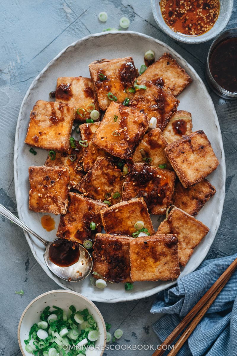 Crispy Marinated Tofu | This recipe generates the most flavorful marinated tofu! The tofu pieces are soaked in a savory spicy Asian sauce, then pan fried until crispy. It’s very easy to put together and yields crispy tofu bites that are bursting with flavor! {Vegan, Gluten-Free adaptable} Crispy marinated tofu in a plate