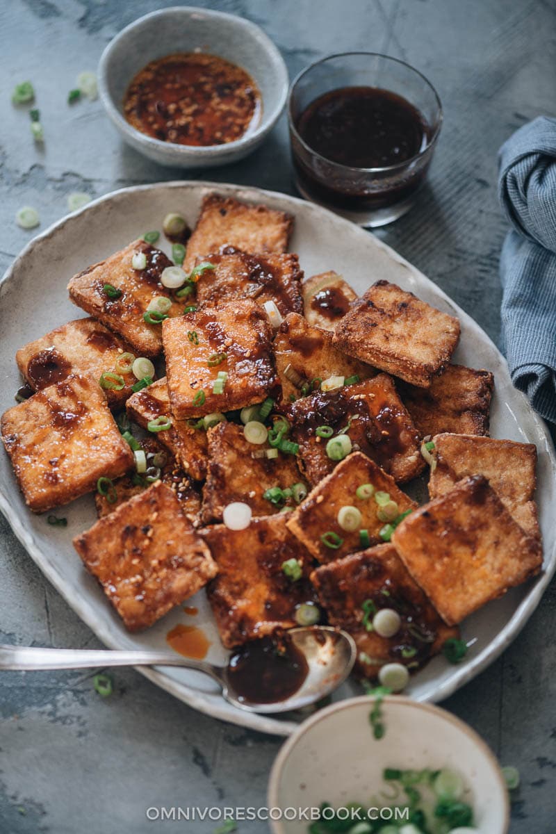 Crispy Marinated Tofu | This recipe generates the most flavorful marinated tofu! The tofu pieces are soaked in a savory spicy Asian sauce, then pan fried until crispy. It’s very easy to put together and yields crispy tofu bites that are bursting with flavor! {Vegan, Gluten-Free adaptable} Crispy tofu served with dipping sauce