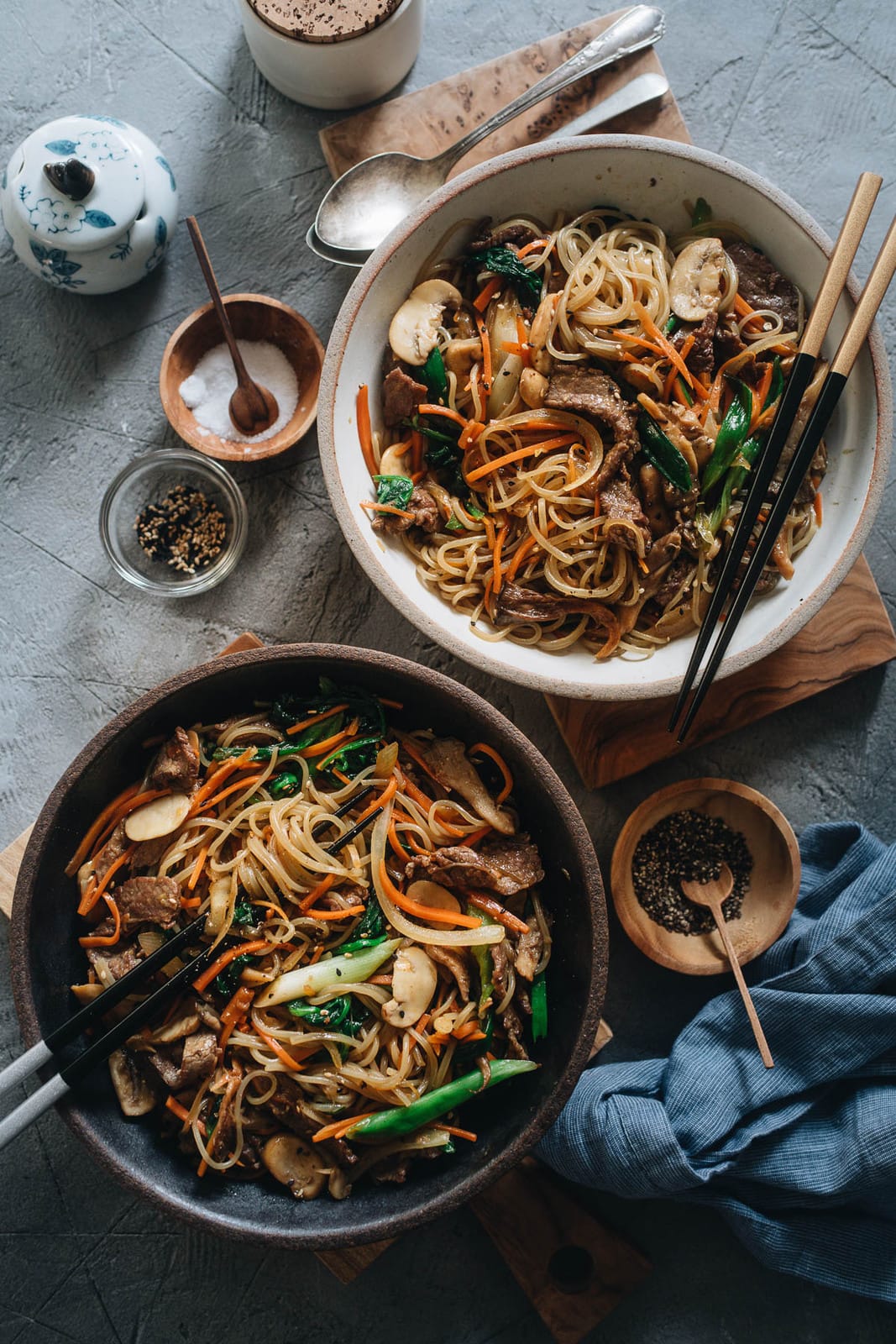 Japchae (Korean Sweet Potato Noodles) | Make japchae at home for a comforting, delicious, and nutritionally balanced weekday dinner. The tender sweet potato noodles are tossed with charred beef and crispy veggies in a sweet savory sauce. This easy recipe uses shortcuts to make the cooking process faster than the traditional recipe. {Gluten Free adaptable, vegan adaptable} Korean sweet potato noodles bowls