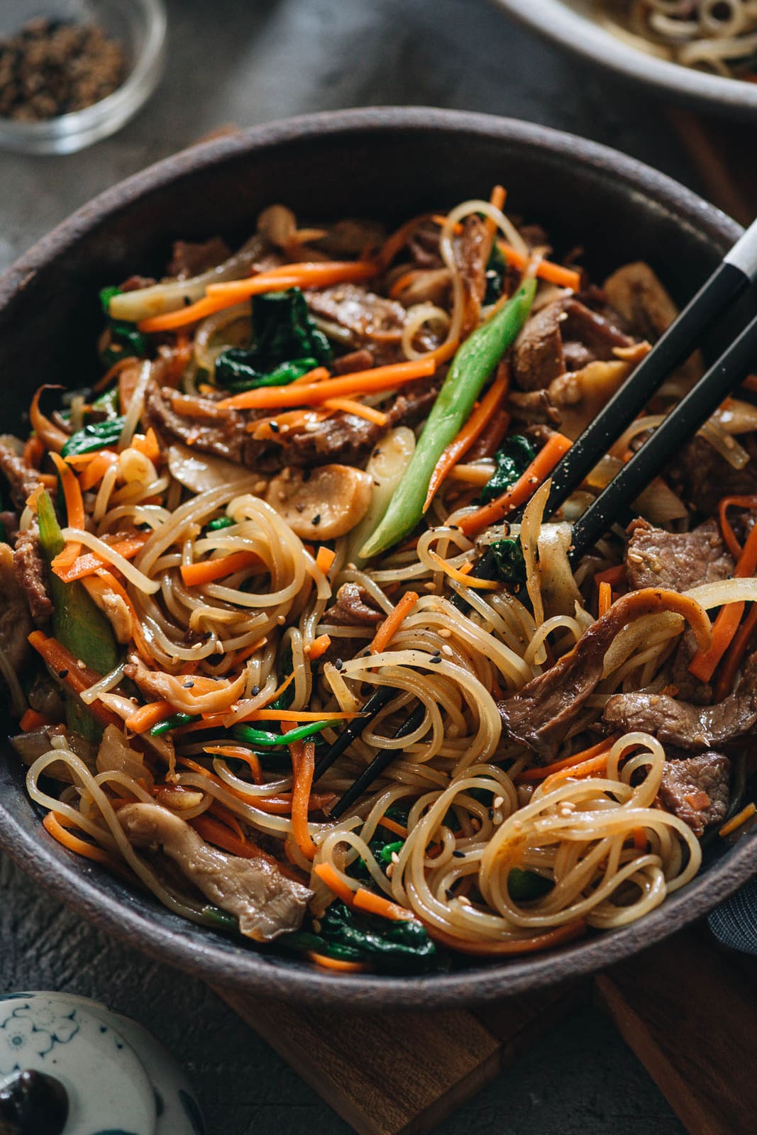 Japchae (Korean Sweet Potato Noodles) | Make japchae at home for a comforting, delicious, and nutritionally balanced weekday dinner. The tender sweet potato noodles are tossed with charred beef and crispy veggies in a sweet savory sauce. This easy recipe uses shortcuts to make the cooking process faster than the traditional recipe. {Gluten Free adaptable, vegan adaptable} Japchae closeup