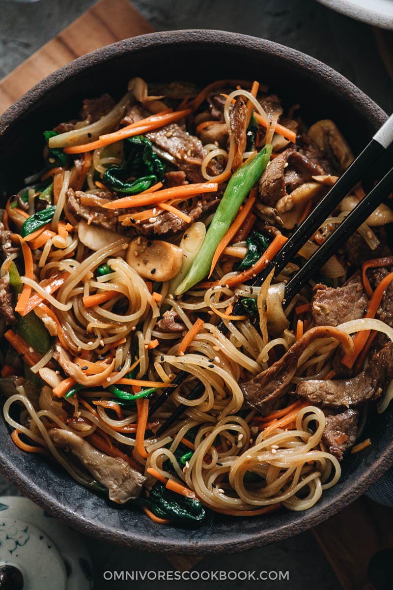 Japchae (Korean Sweet Potato Noodles) | Make japchae at home for a comforting, delicious, and nutritionally balanced weekday dinner. The tender sweet potato noodles are tossed with charred beef and crispy veggies in a sweet savory sauce. This easy recipe uses shortcuts to make the cooking process faster than the traditional recipe. {Gluten Free adaptable, vegan adaptable} Korean sweet potato noodles with beef