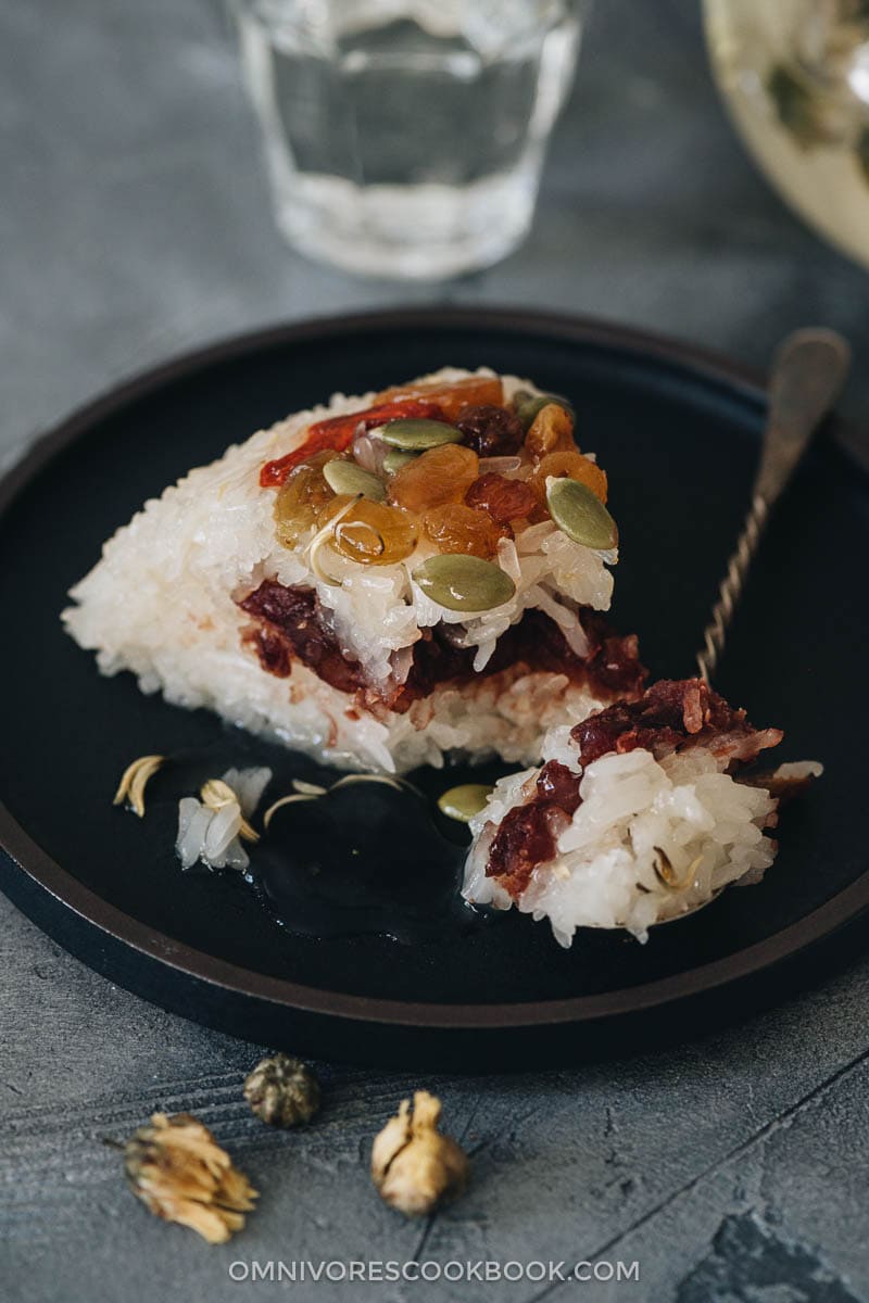 Eight Treasure Rice (八宝饭, Chinese Rice Pudding) | Lightly sweetened sticky rice stuffed with red bean paste and topped with dried fruits and seeds, then served with a fragrant chrysanthemum syrup that has an amazing earthy aroma. The modernized version tastes so good and uses ingredients that are easy to source. And the cooking is quite simple. It’s a light and healthy dessert that is perfect to serve at the end of a meal. {Vegan, Gluten-Free} Chinese rice pudding with toppings and red bean paste