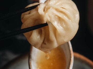 Homemade soup dumplings dripping soup into a spoon