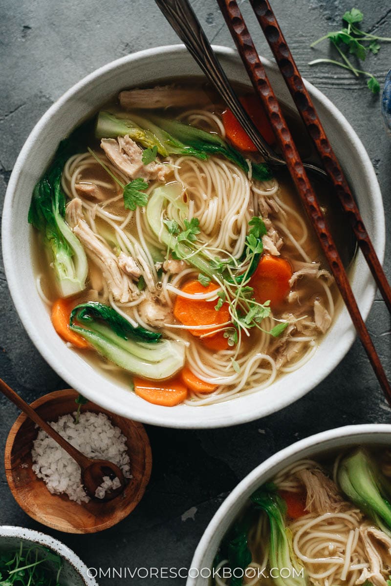 Bowl of noodle soup with shredded chicken, carrot and baby bok choy