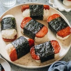 The spam is grilled until crispy, perfectly caramelized with soy sauce and sugar, and wrapped together with sushi rice. Made ahead of time, these Spam musubi are perfect for your lunchbox, appetizer platter, or potluck. They are also a fantastic game-day snack. This recipe uses just the right amount of seasoning to create a balanced flavor that’s addictively tasty.