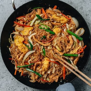 Stir fried rice noodles with chicken, eggs and vegetables in a pan