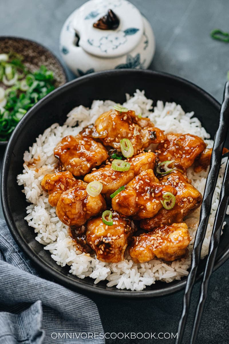 Crispy sesame chicken over steamed rice close up