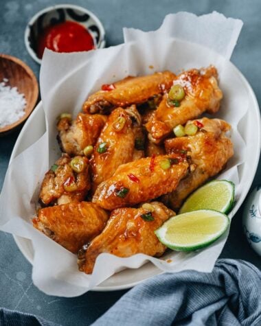 Crispy air fryer wings coated with sauce and served with lime and hot sauce