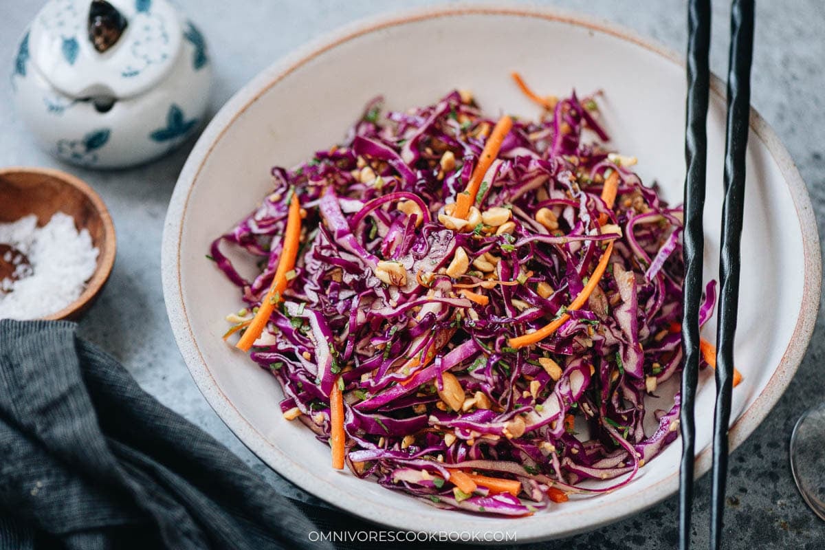 Close-up of crunchy Chinese coleslaw with purple cabbage, carrots, peanuts, and herbs in soy-vinegar dressing.