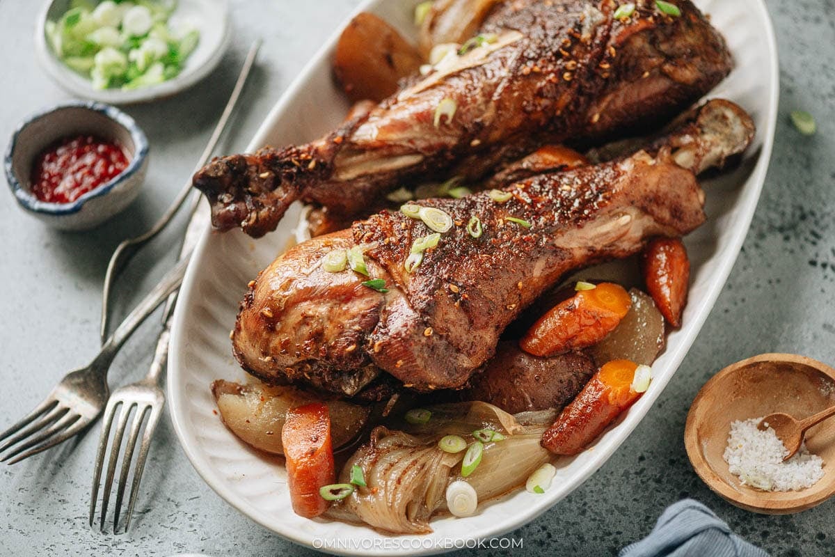 Roast turkey legs over a bed of vegetable served in a platter