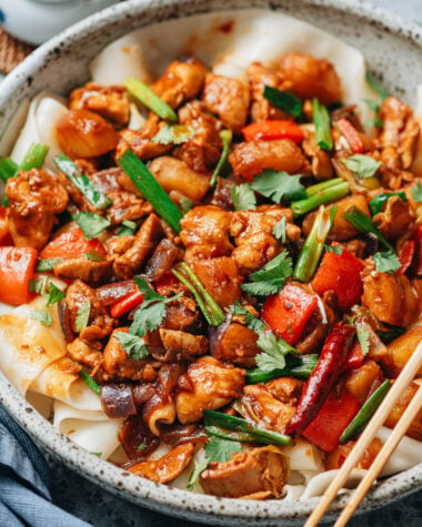 Close-up of Big Plate Chicken showing tender chicken pieces, soft potatoes, red peppers, and scallions coated in rich spicy sauce.