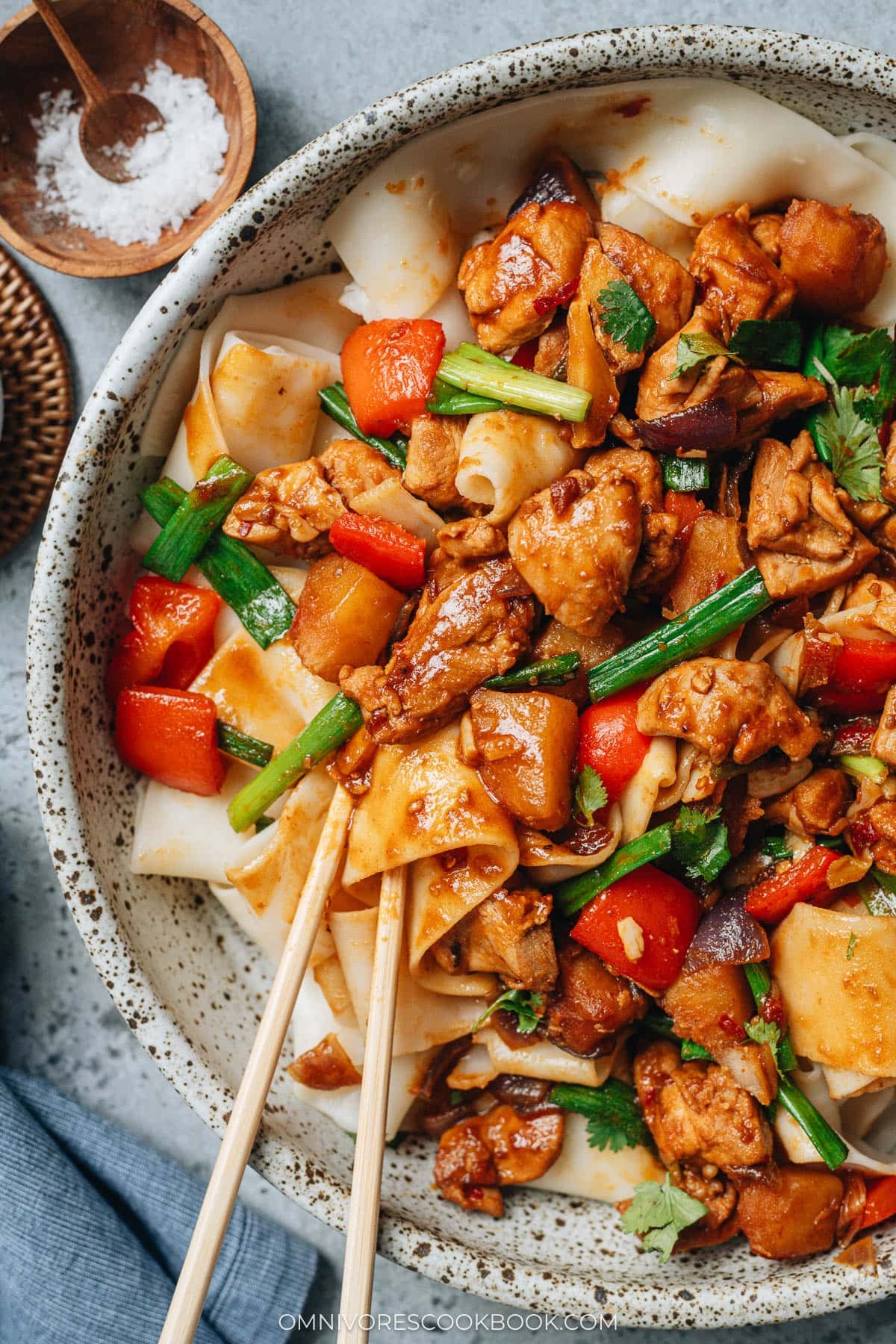 Chopsticks lifting noodles and chicken pieces, showing the thick sauce coating the ingredients of Da Pan Ji.