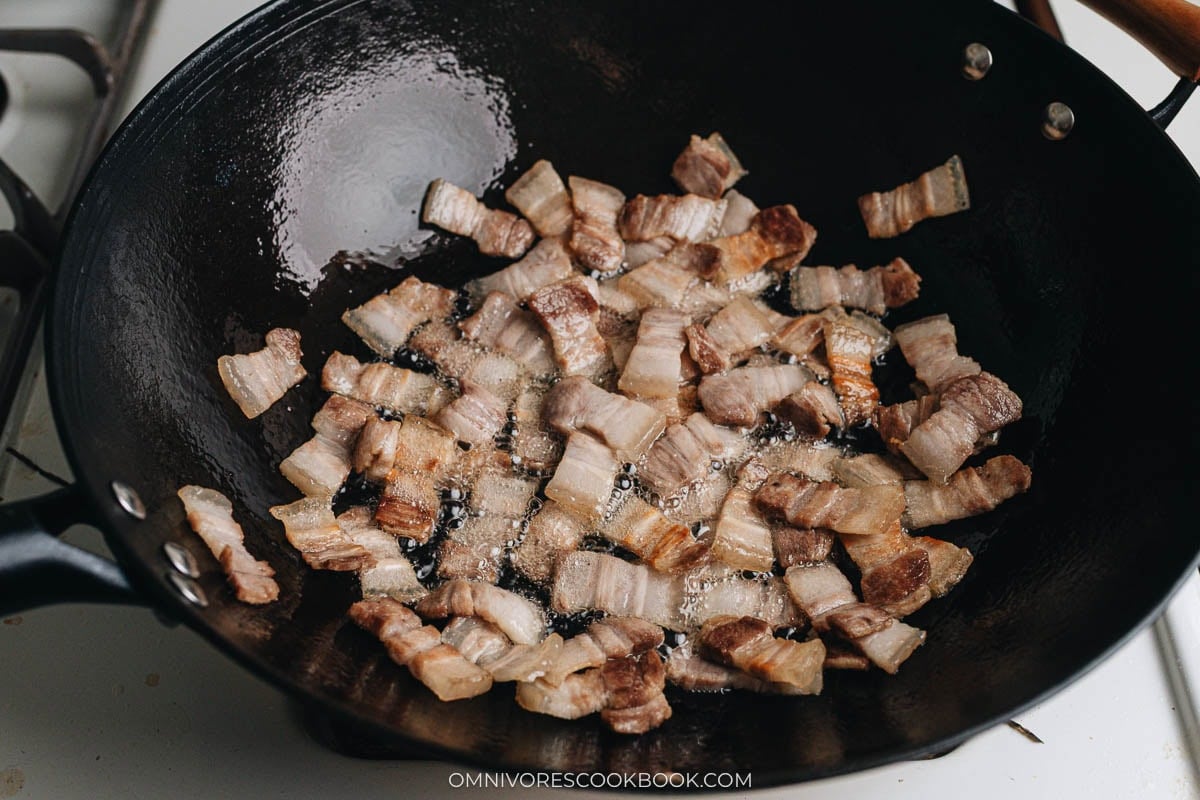 Pork belly slices sizzling in a wok.