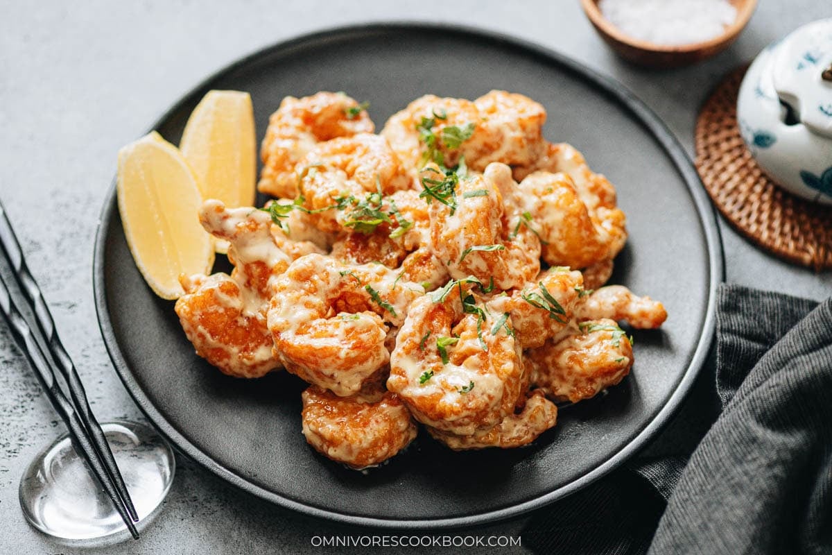 Crispy fried shrimp tossed in creamy wasabi mayo sauce, garnished with cilantro, with lemon on the side.