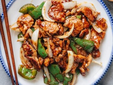 Pork and pepper stir fry plated with chopsticks on the side