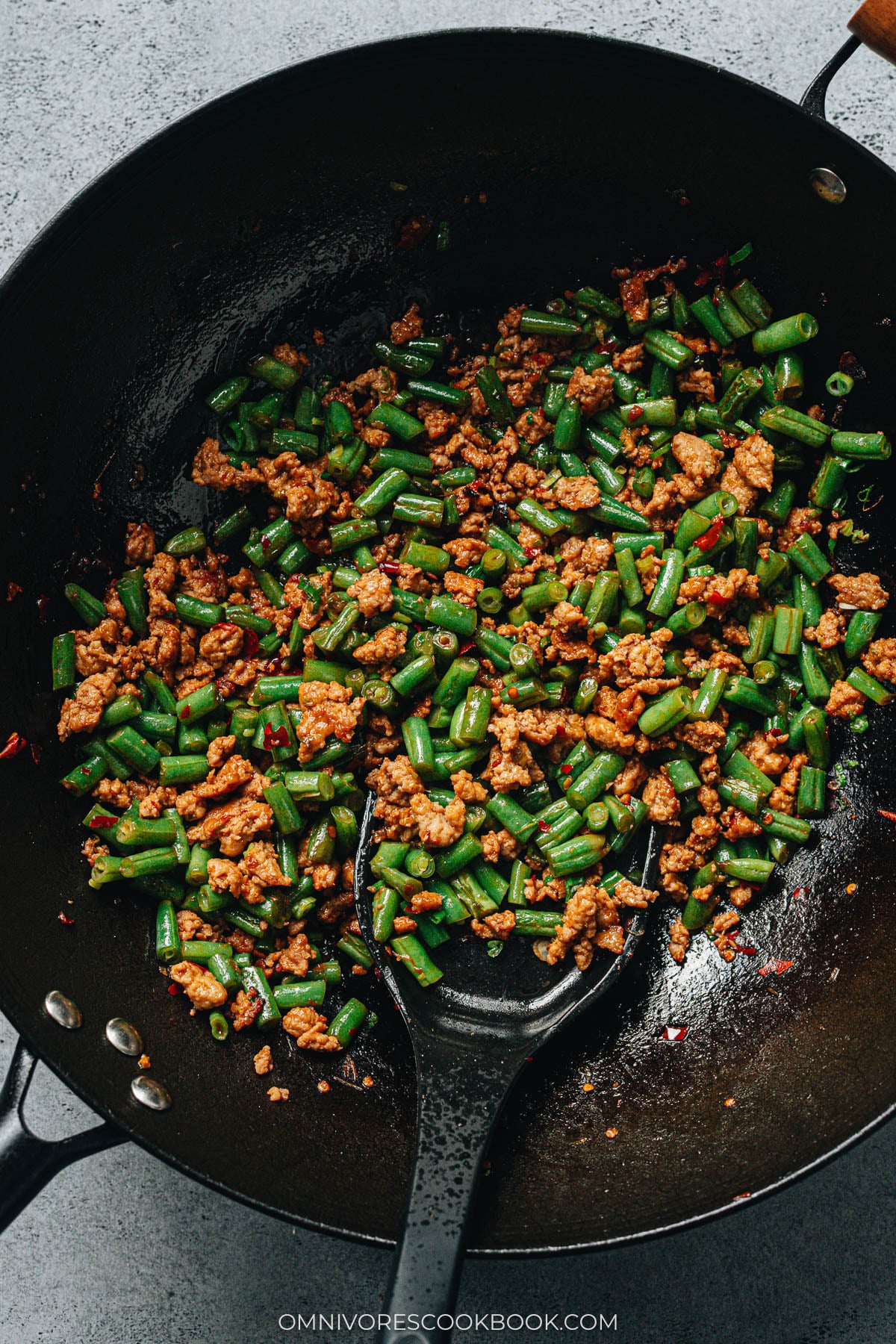 Chinese stir-fried green beans with ground pork cooking in a wok