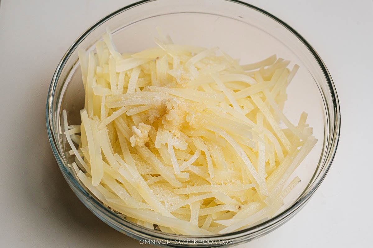 Seasoning julienned potatoes with garlic and salt