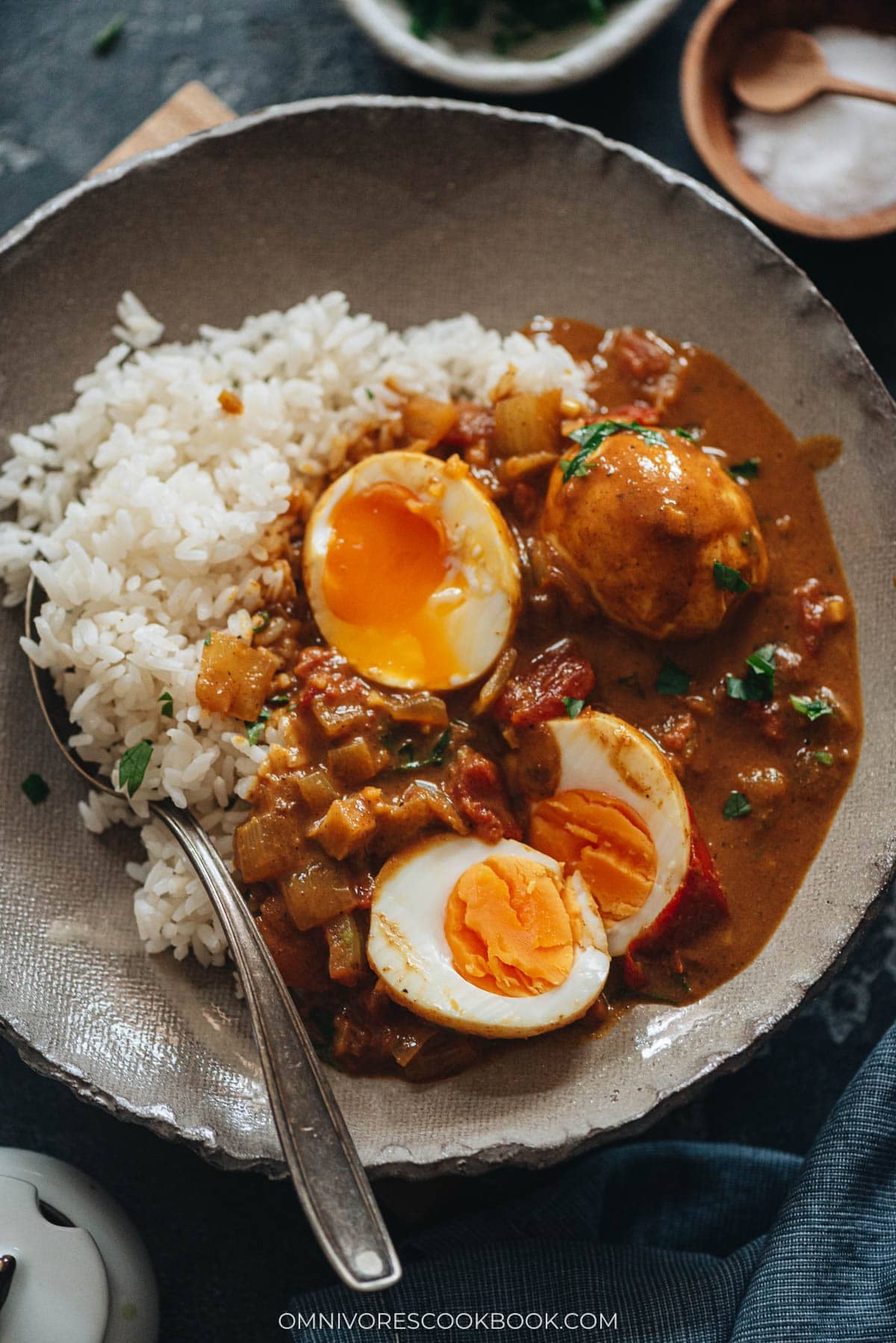 Easy Egg Curry - Tender eggs are smothered in a super rich curry sauce with a tomato and coconut base. The recipe shows you how to cook a tasty curry using minimal ingredients, making it a perfect dish for a busy weekday dinner. {Gluten-Free} Egg curry served with steamed rice in a bowl