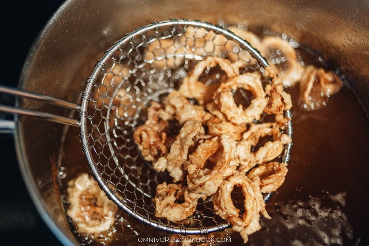 frying the squid using a slotted spoon