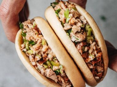 Flatlay of pork belly buns with chopped cilantro and Sriracha sauce