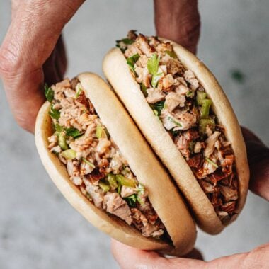 Flatlay of pork belly buns with chopped cilantro and Sriracha sauce