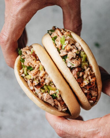 Flatlay of pork belly buns with chopped cilantro and Sriracha sauce